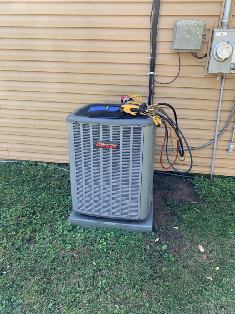 Tom's Heating & Air tech tools on an Amana outdoor unit during a River Valley service call